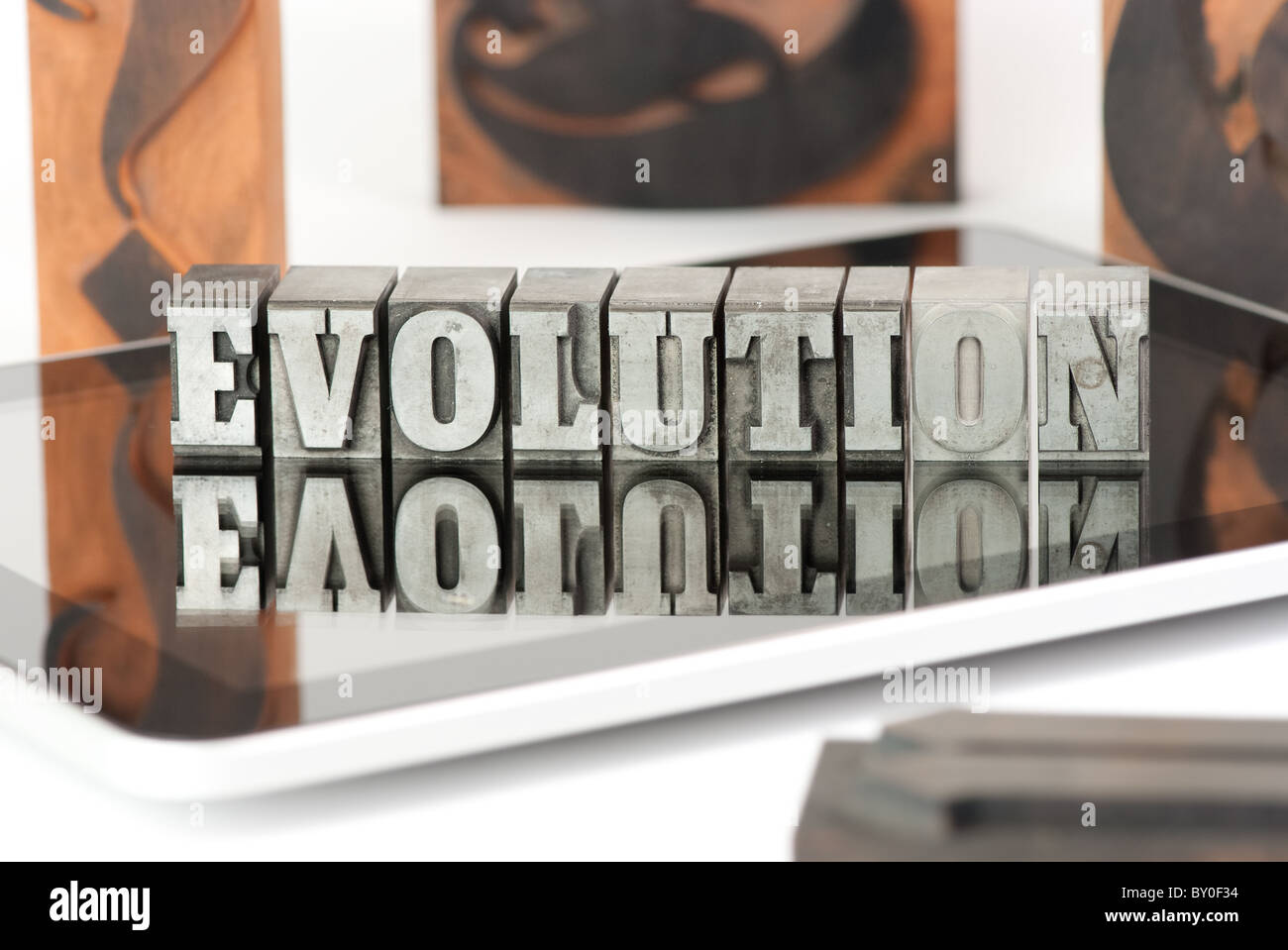 The word EVOLUTION in plumb letters, standing on a tablet pc, surrounded by wooden letters Stock Photo