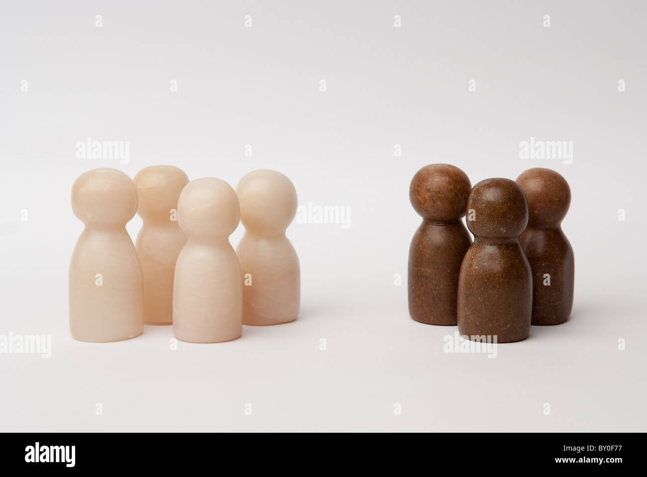 4 white and 3 brown figures, building 2 seperate groups Stock Photo