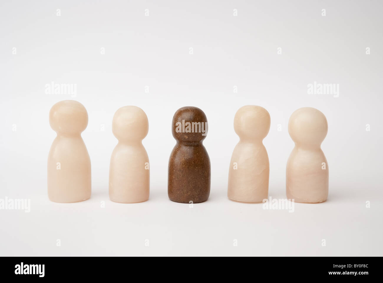A brown figure integrated in a group of 4 white figures Stock Photo