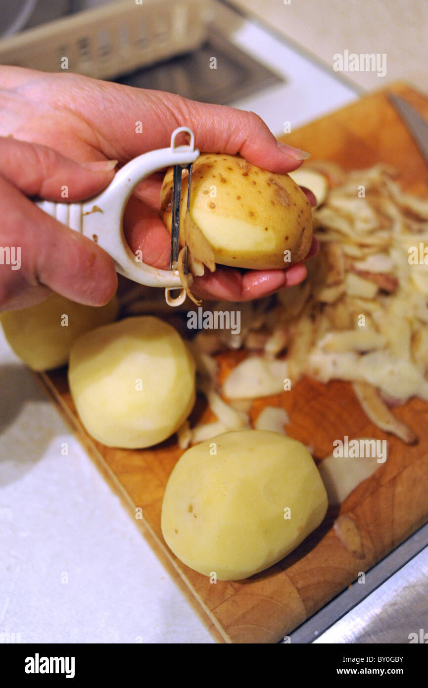 Peeling potatoes with peeler in a kitchen Stock Photo Alamy