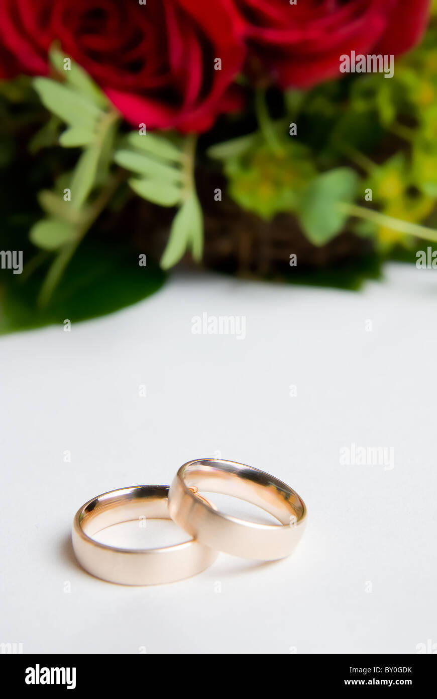 Two wedding rings in front of red roses Stock Photo