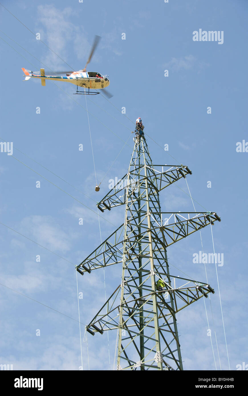 Helicopter connecting power lines, worker on an electricity pylon
