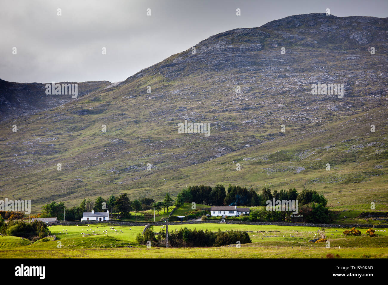 Homes nestling at the foot of the Maumturk Mountains near Recess, Connemara, County Galway, Ireland Stock Photo