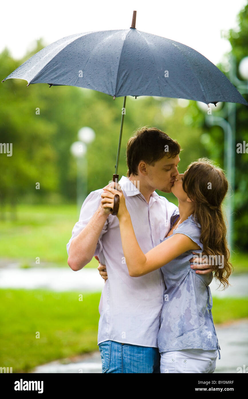 Two People Kissing In The Rain Under An Umbrella