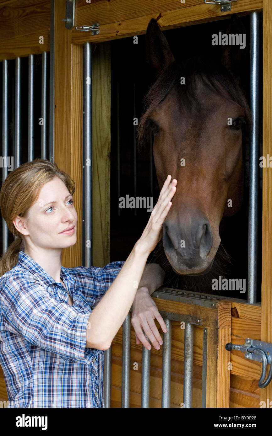 Mid adult woman with horse in stable Stock Photo
