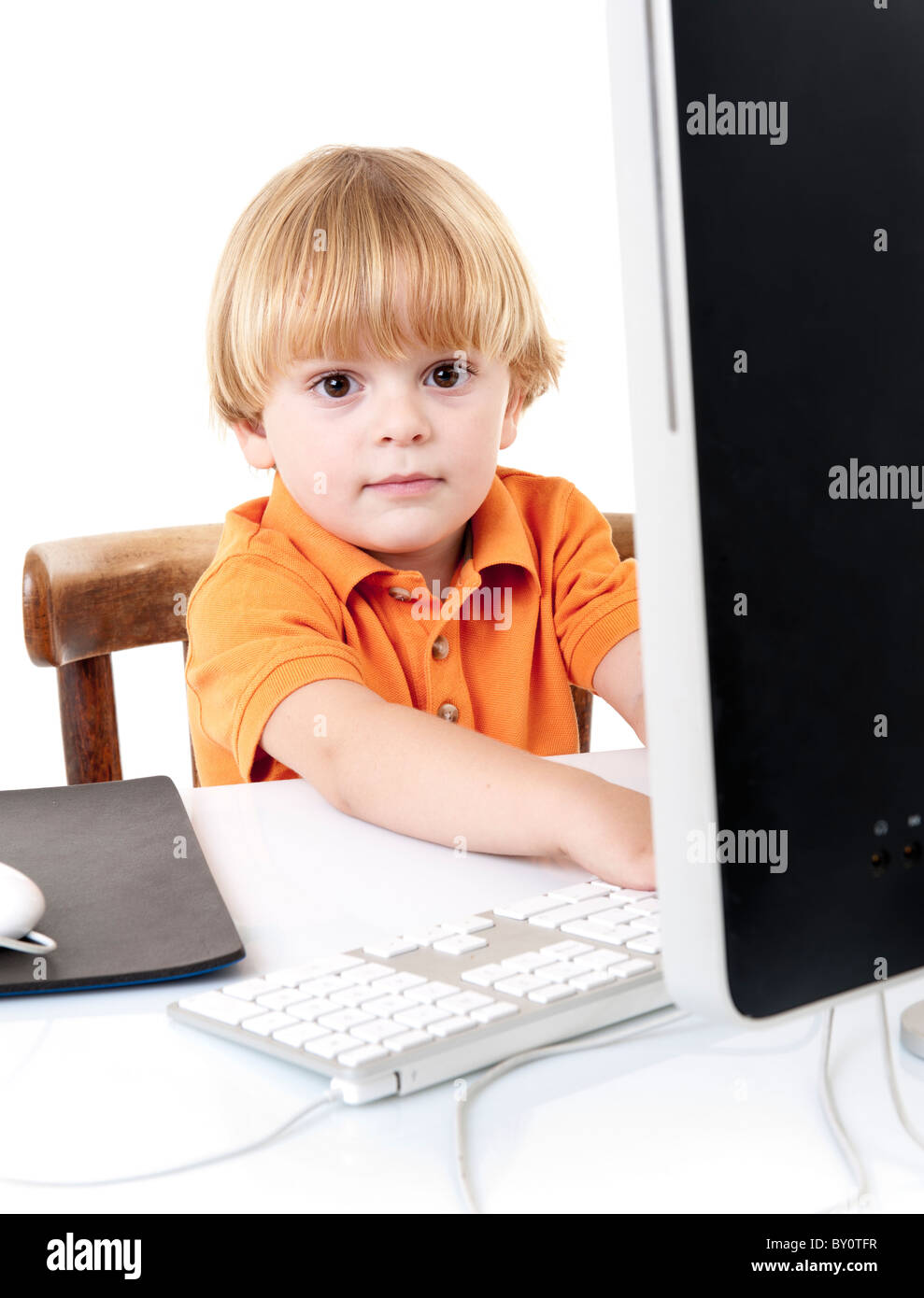 young boy with desktop computer looking at camera isolated on white