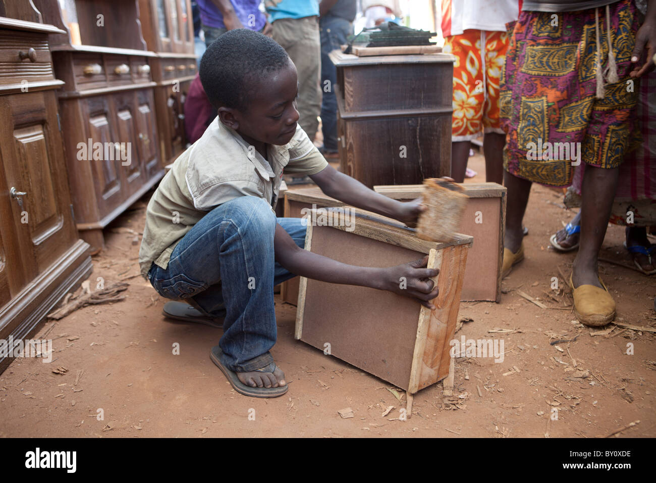 NAMPULA, MOZAMBIQUE, May 2010 : Sunday Market - a boy polishing a draw front for a wooden furniture seller. Stock Photo