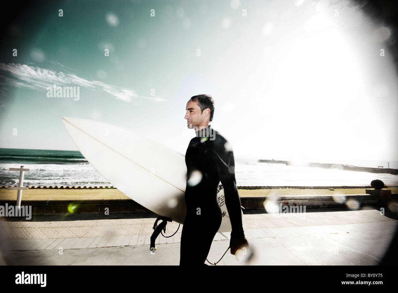 Man holding a surfboard leaving beach Stock Photo Alamy