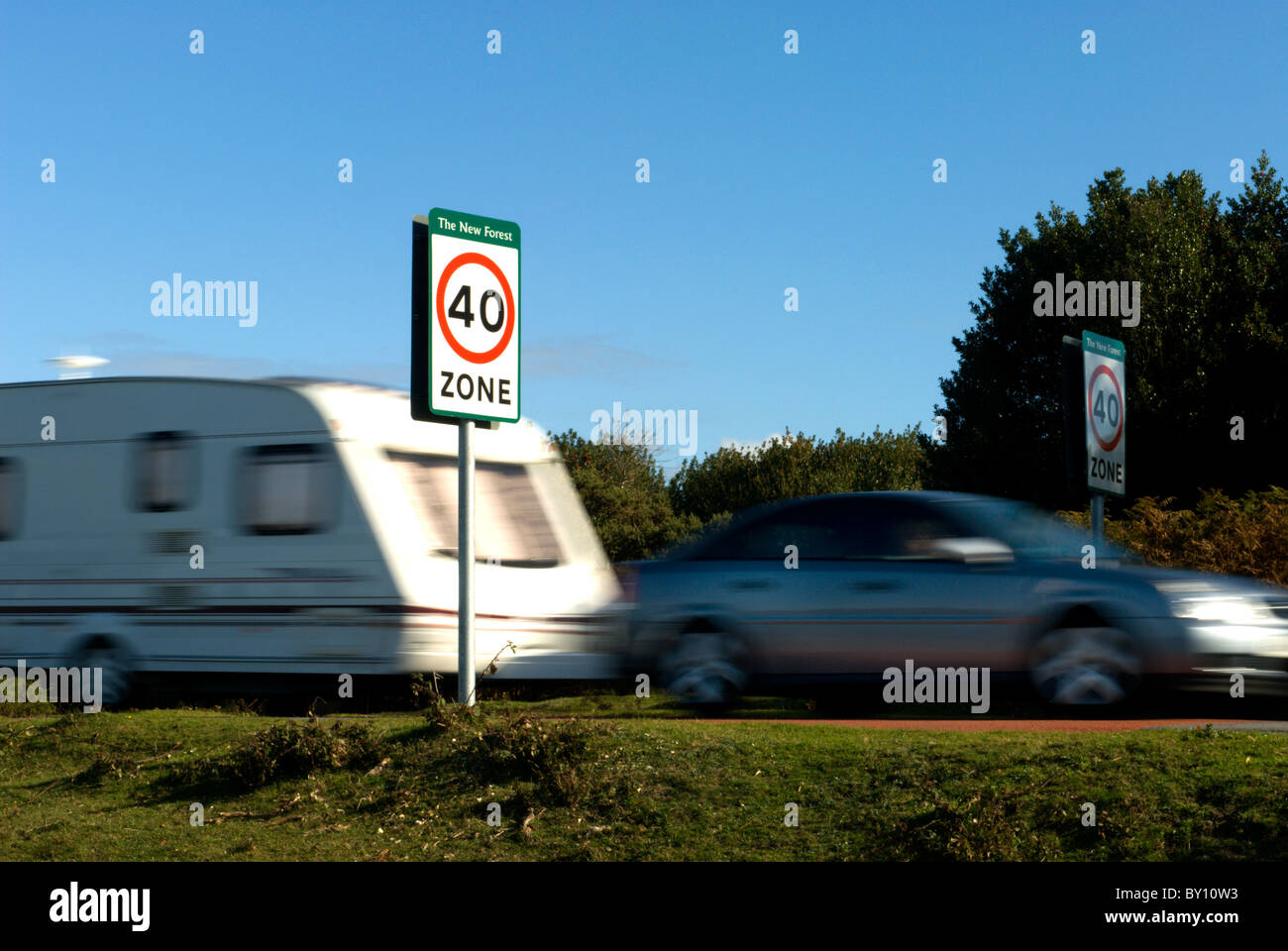 A car and caravan passing signage showing there is a 40 mph speed limit within the New Forest National Park Stock Photo