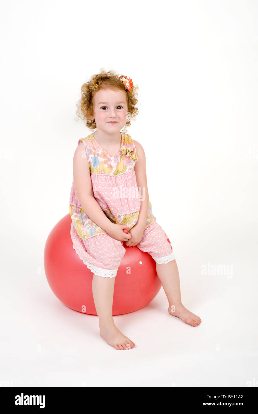 young girl on a red space hopper isolated on white Stock Photo