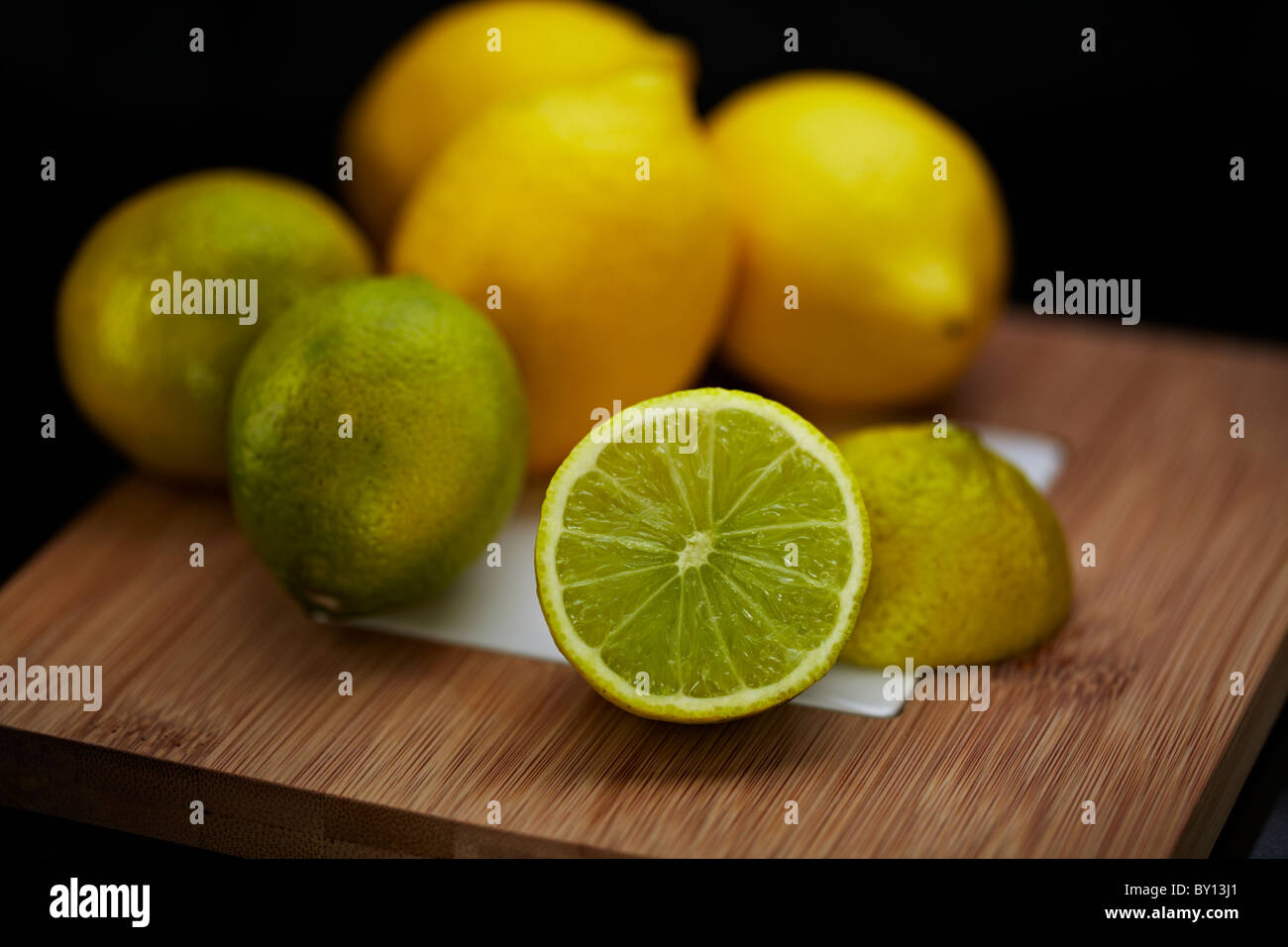 Citrus fruit (lemons and limes) on a bamboo wooden chopping board Stock Photo