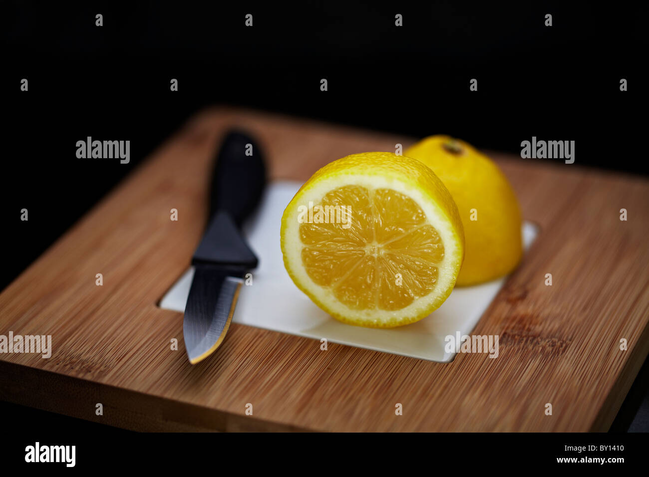 Citrus fruit (lemons and limes) on a bamboo wooden chopping board Stock Photo