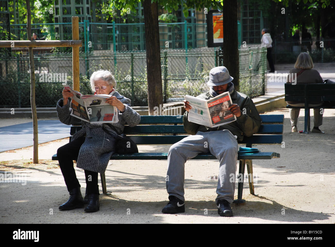 people reading newspaper on Paris park bench France Stock Photo