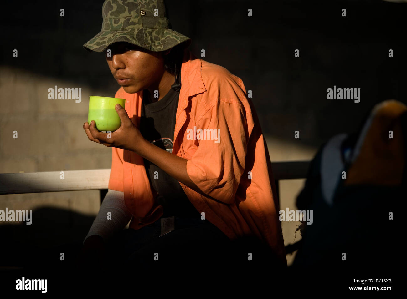 A Central American migrant drinks coffee in a shelter located along the railroad in Ixtepec, Oaxaca, Mexico. Stock Photo