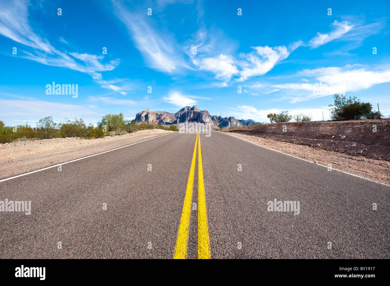 A remote and deserted desert road with a beautiful sky. Stock Photo
