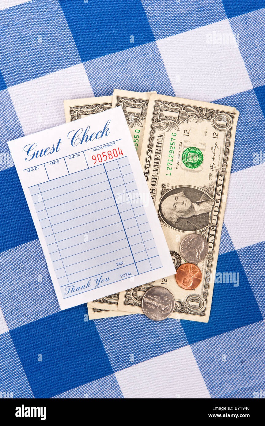 A meal check from a restaurant with change on a checkered table cloth Stock Photo