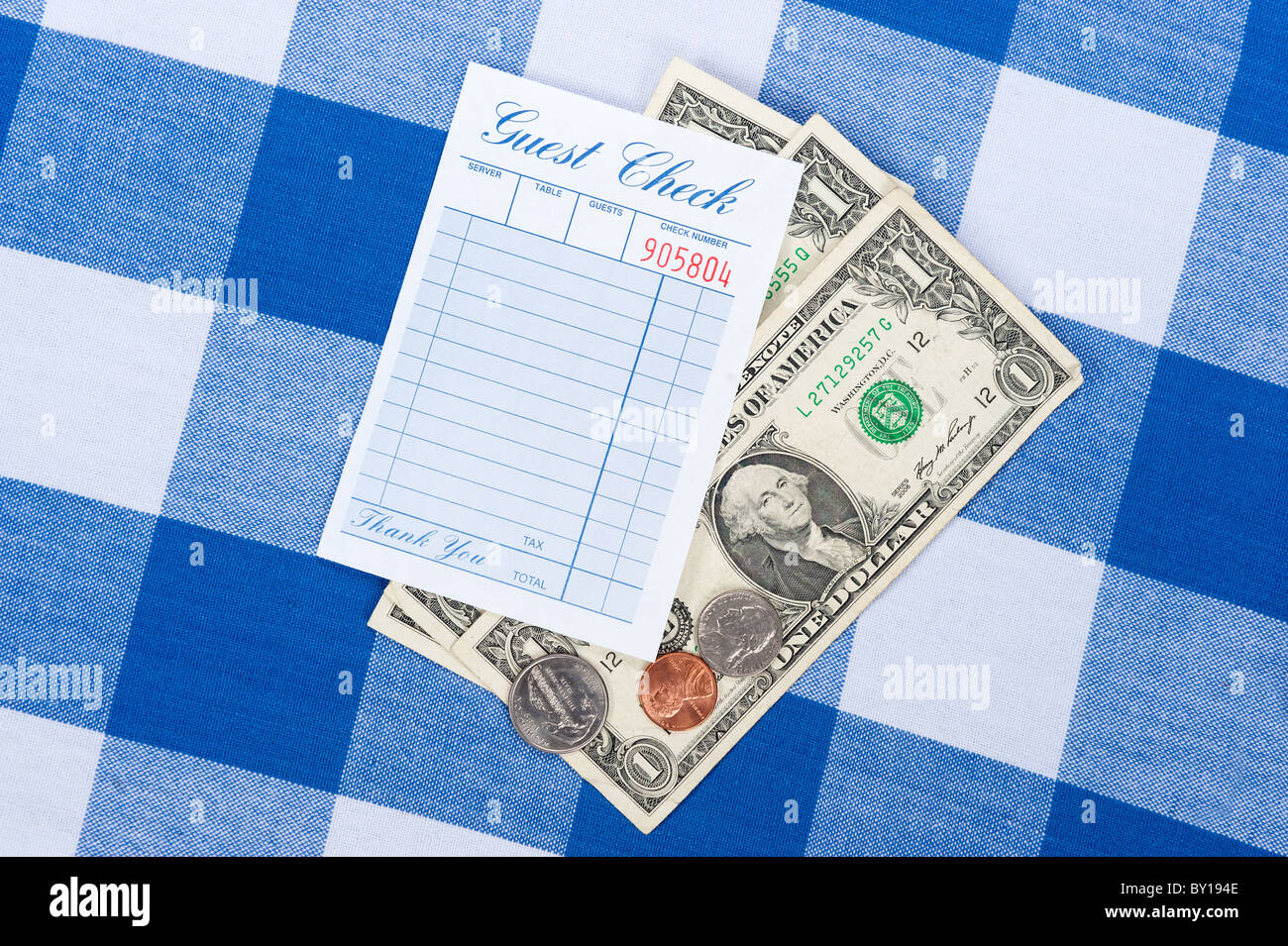 A meal check from a restaurant with change on a checkered table cloth Stock Photo