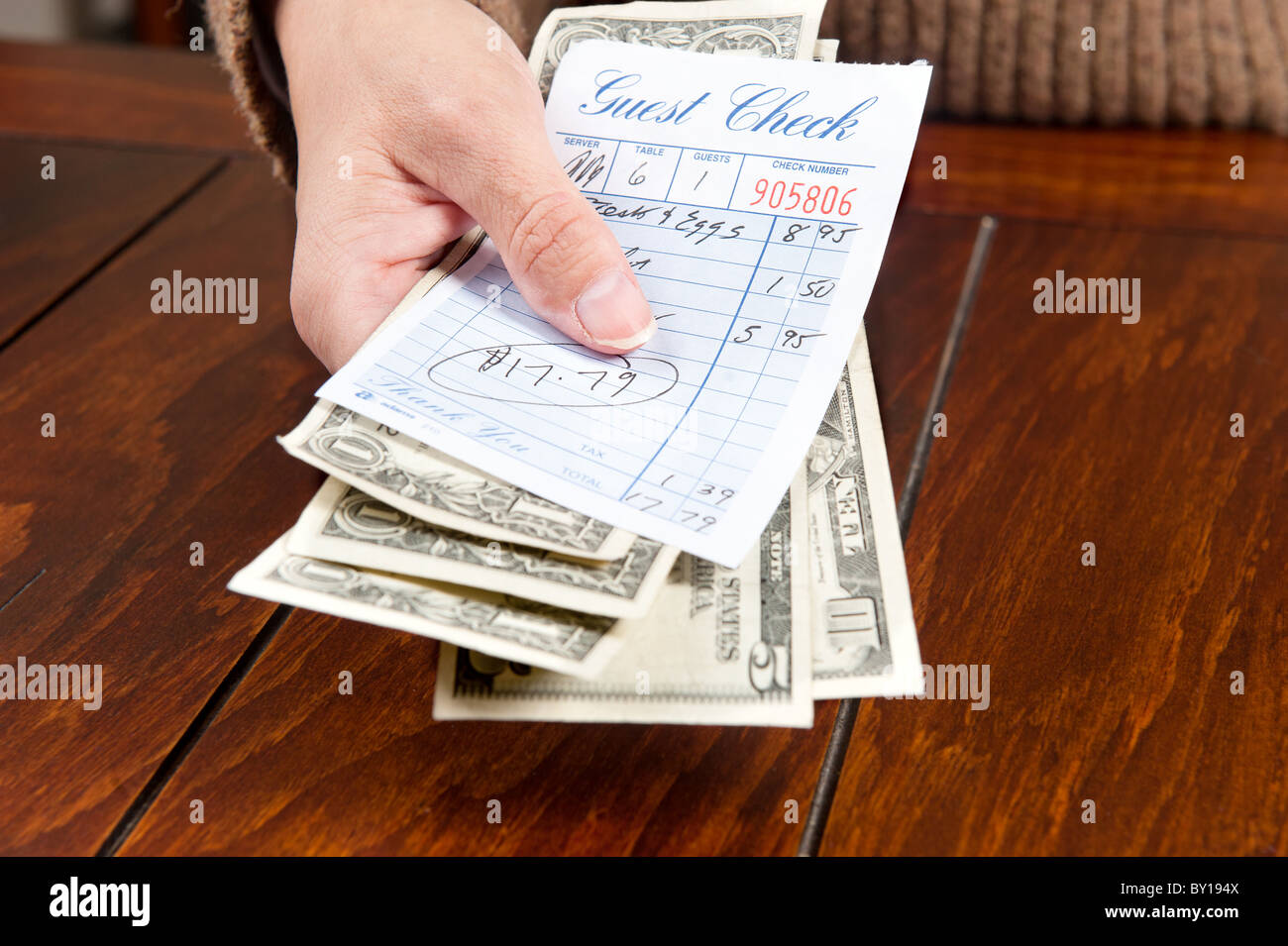 A woman pays her meal bill with cash. Stock Photo