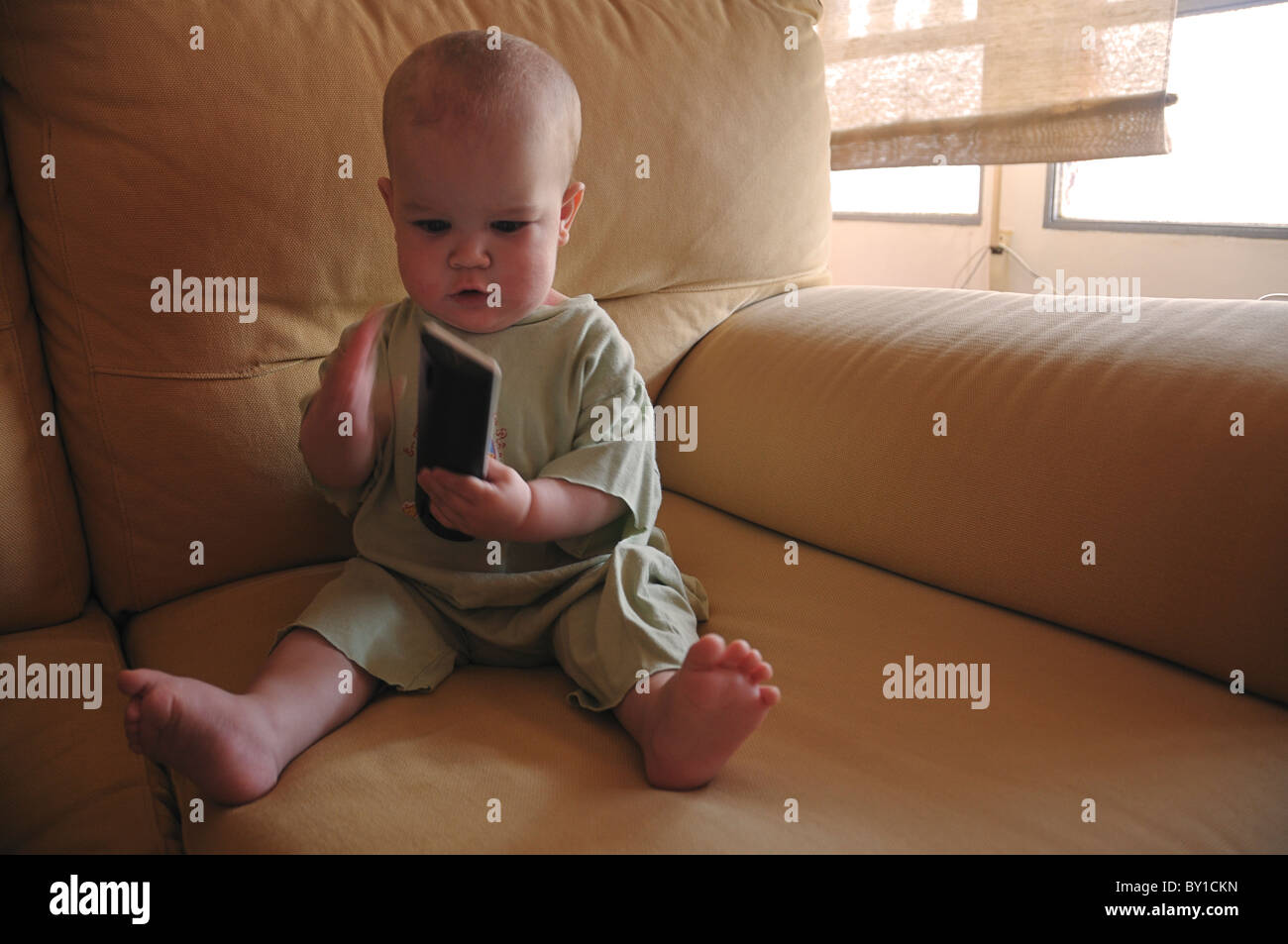 Child playing with a TV remote. Stock Photo