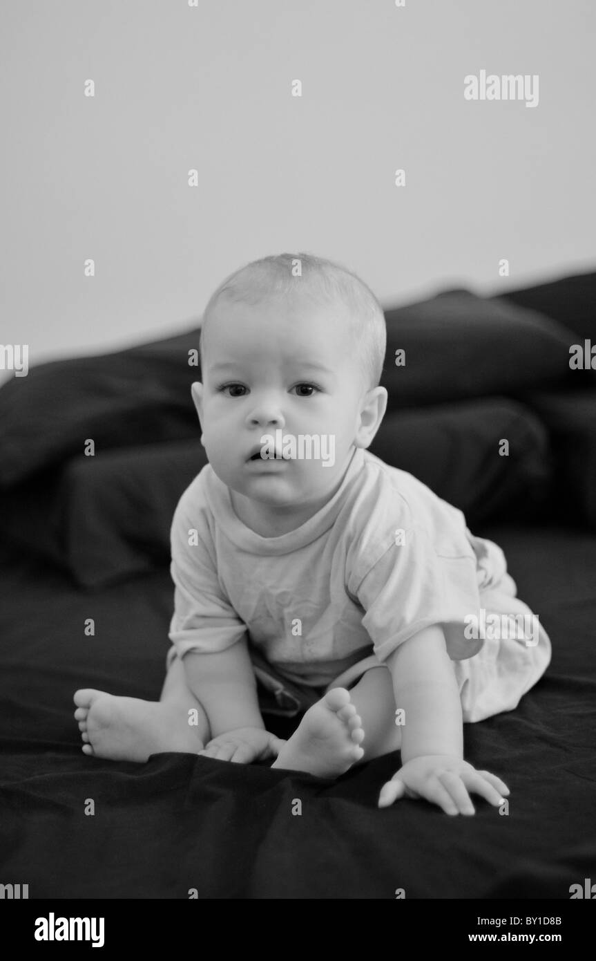 Toddler sitting in a big bed Stock Photo
