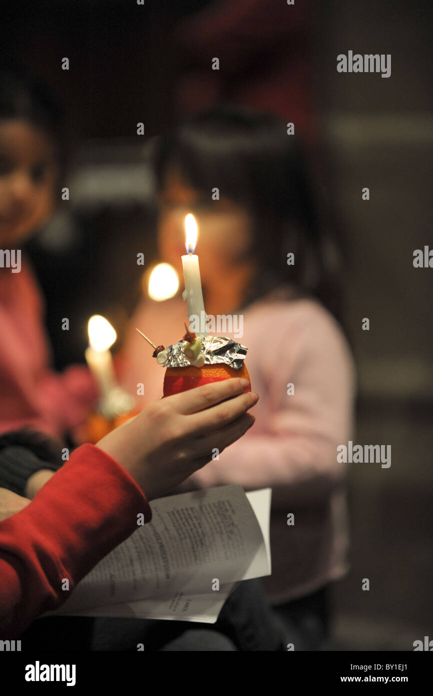 A young girl holds a lit  Christingle during a carol service on Christmas eve in St Peter's Collegiate Church, Wolverhampton Stock Photo