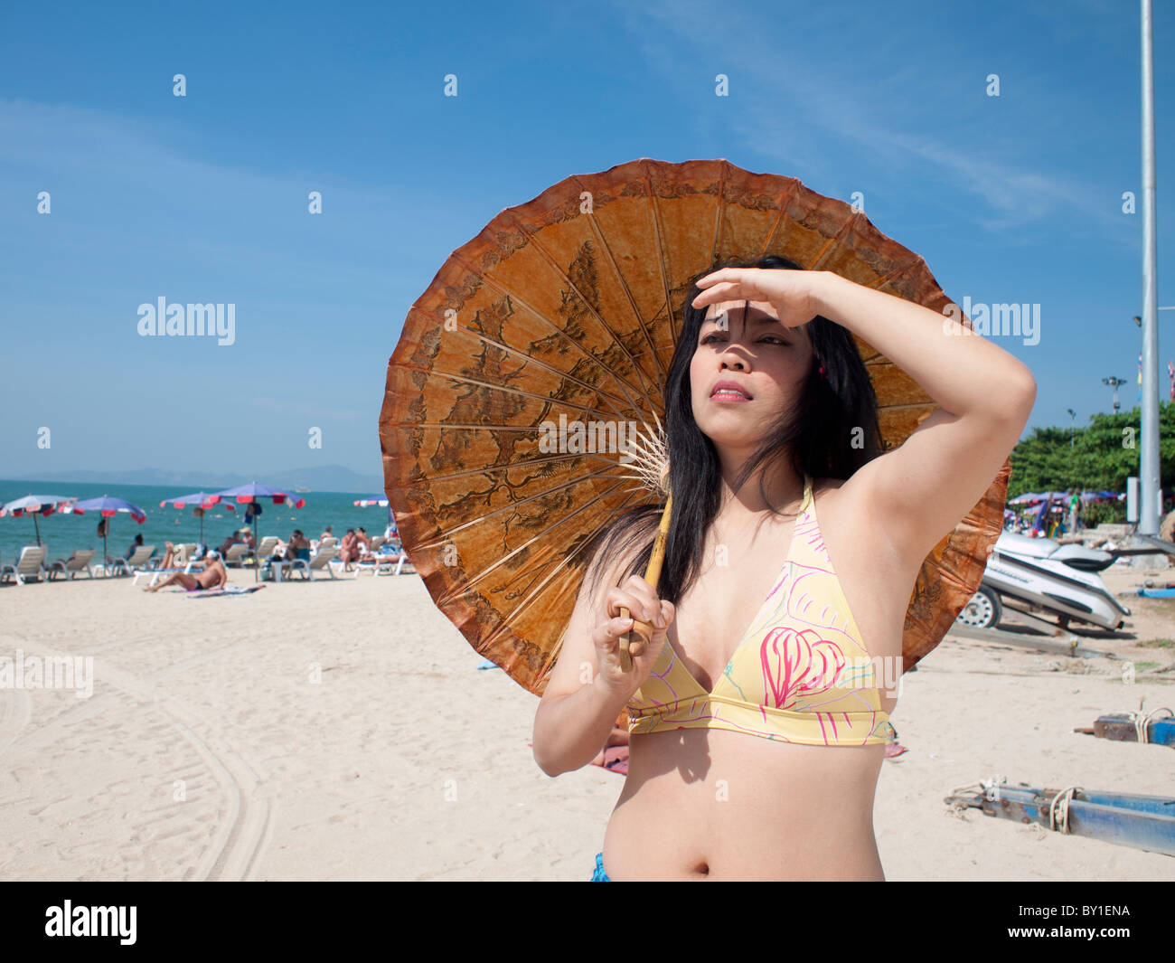 A women with paper umbrella on the very sunshine day at the beach. Stock Photo