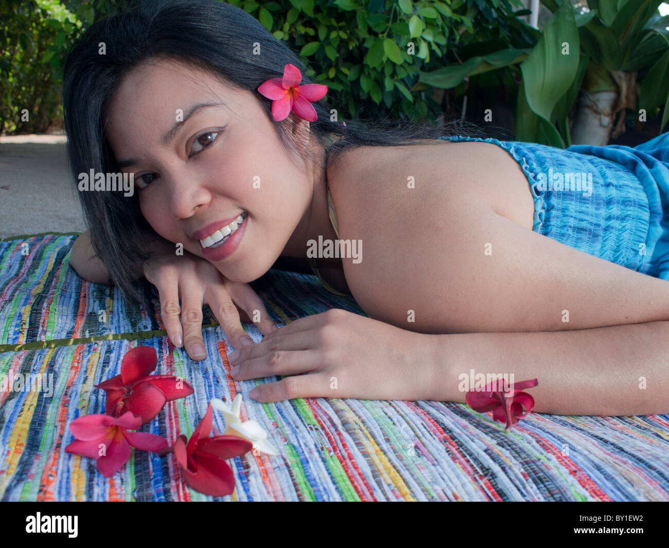 A women laying on the beach with pink plumeria flower Stock Photo