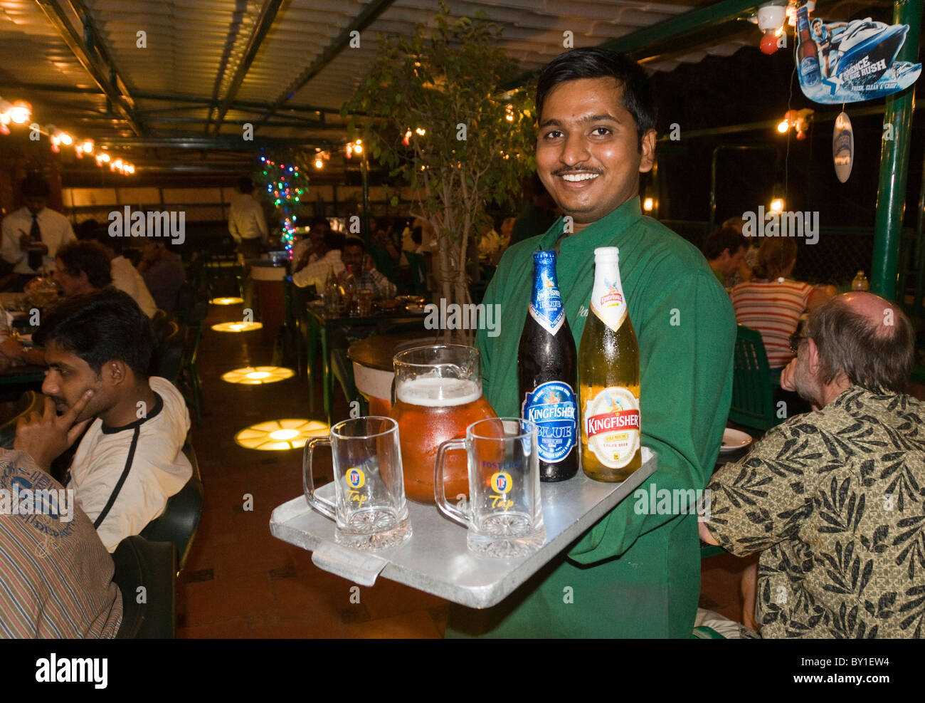 A waiter serving Kingfisher lager beer In a bar restaurant in India Stock Photo
