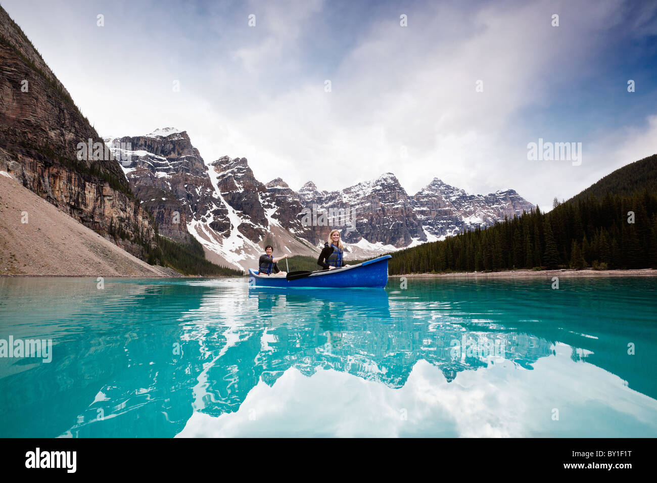 Man and woman sailing on peaceful lake against mountain range Stock Photo