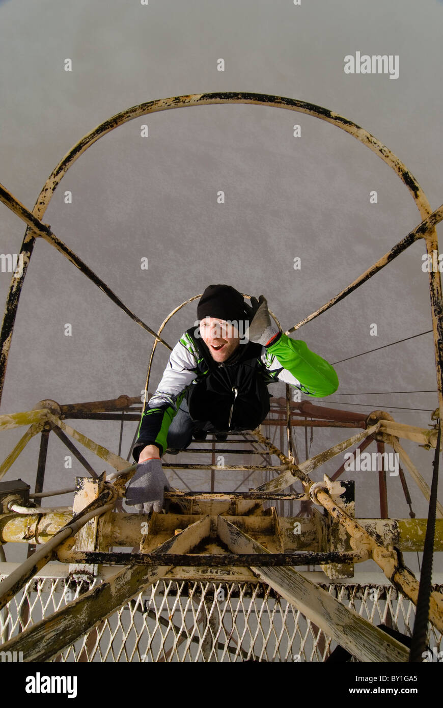 A man climbing up a metal ladder on the outside of a radio antenna