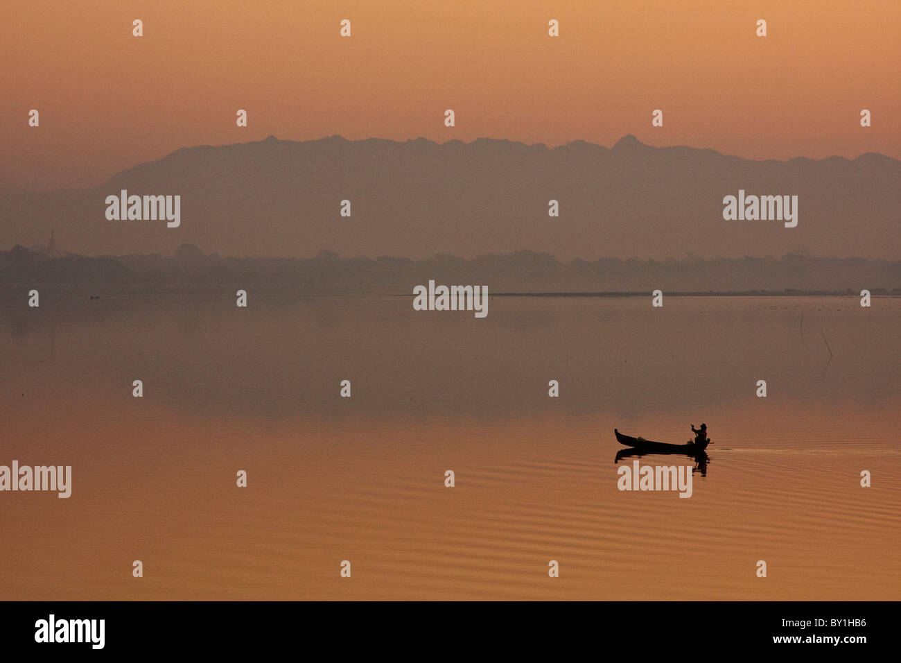 Myanmar, Burma, Amarapura. A fisherman paddling across Taungthaman Lake at sunrise, Amarapura. Stock Photo