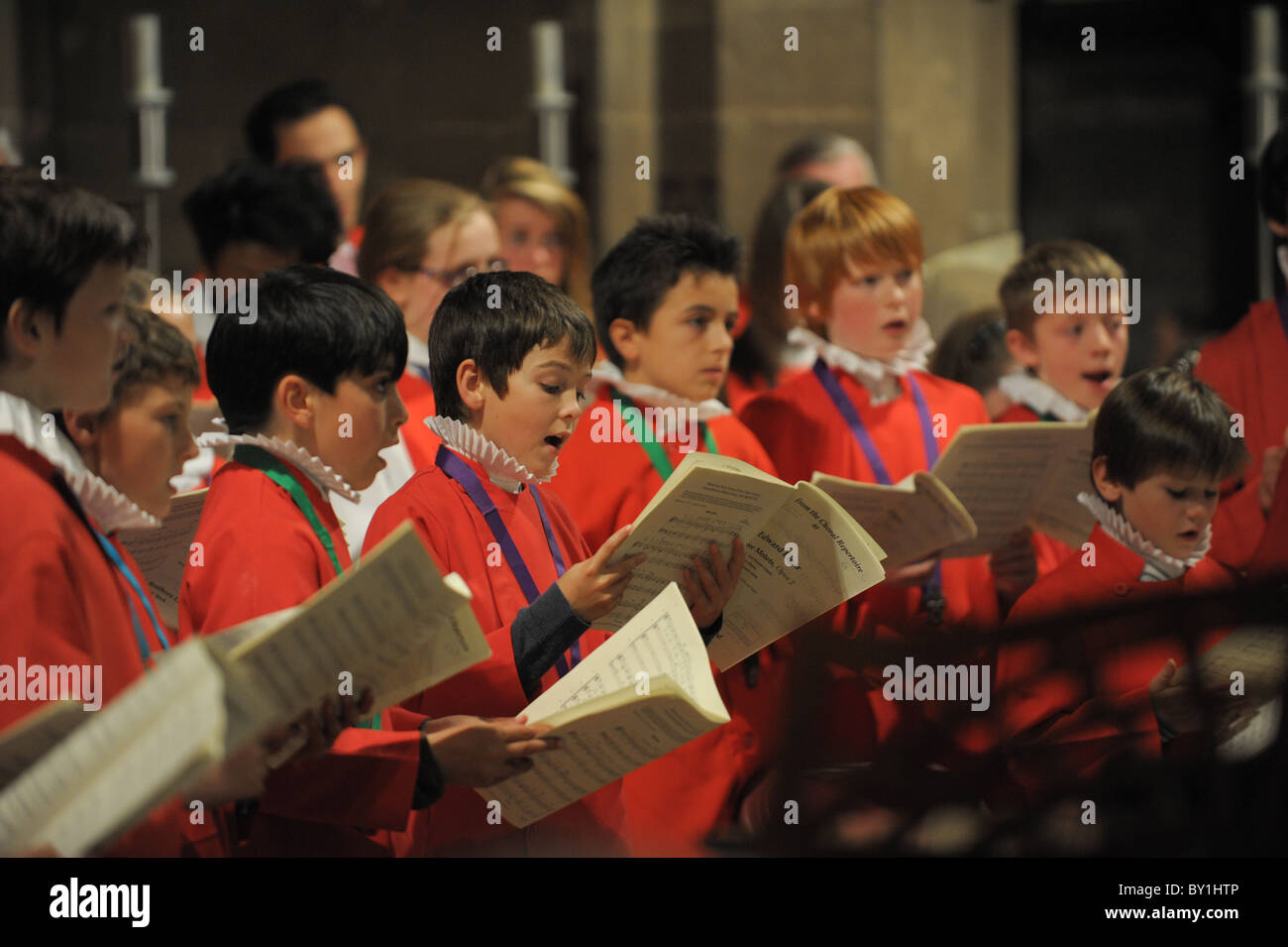 Choirboys in red cassocks and white ruffs holding music and singing at St Peter's Collegiate Church, Wolverhampton Stock Photo