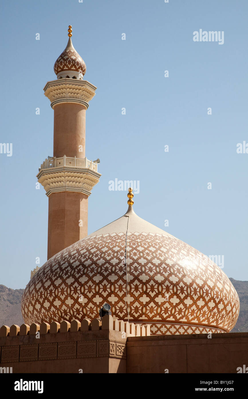 Oman, Nizwa. The iconic dome and minaret of Nizwa Mosque are often used to symbolise Oman. Shown here with the new terracotta Stock Photo