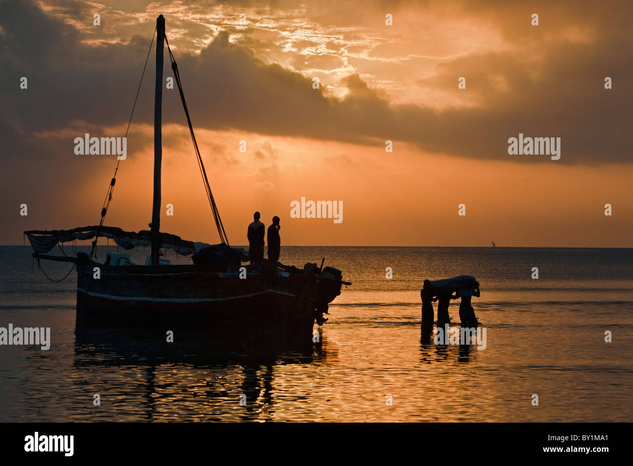 Off-loading cargo from a dhow from Zanzibar at dawn. Stock Photo