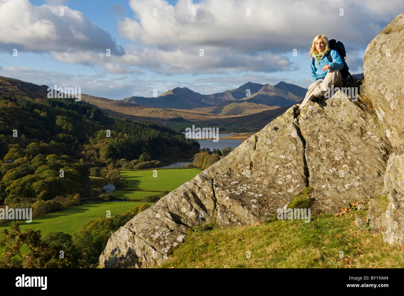 North Wales, Snowdonia.  Woman sitting on rocks against the backdrop of Mt Snowdon. (MR) Stock Photo