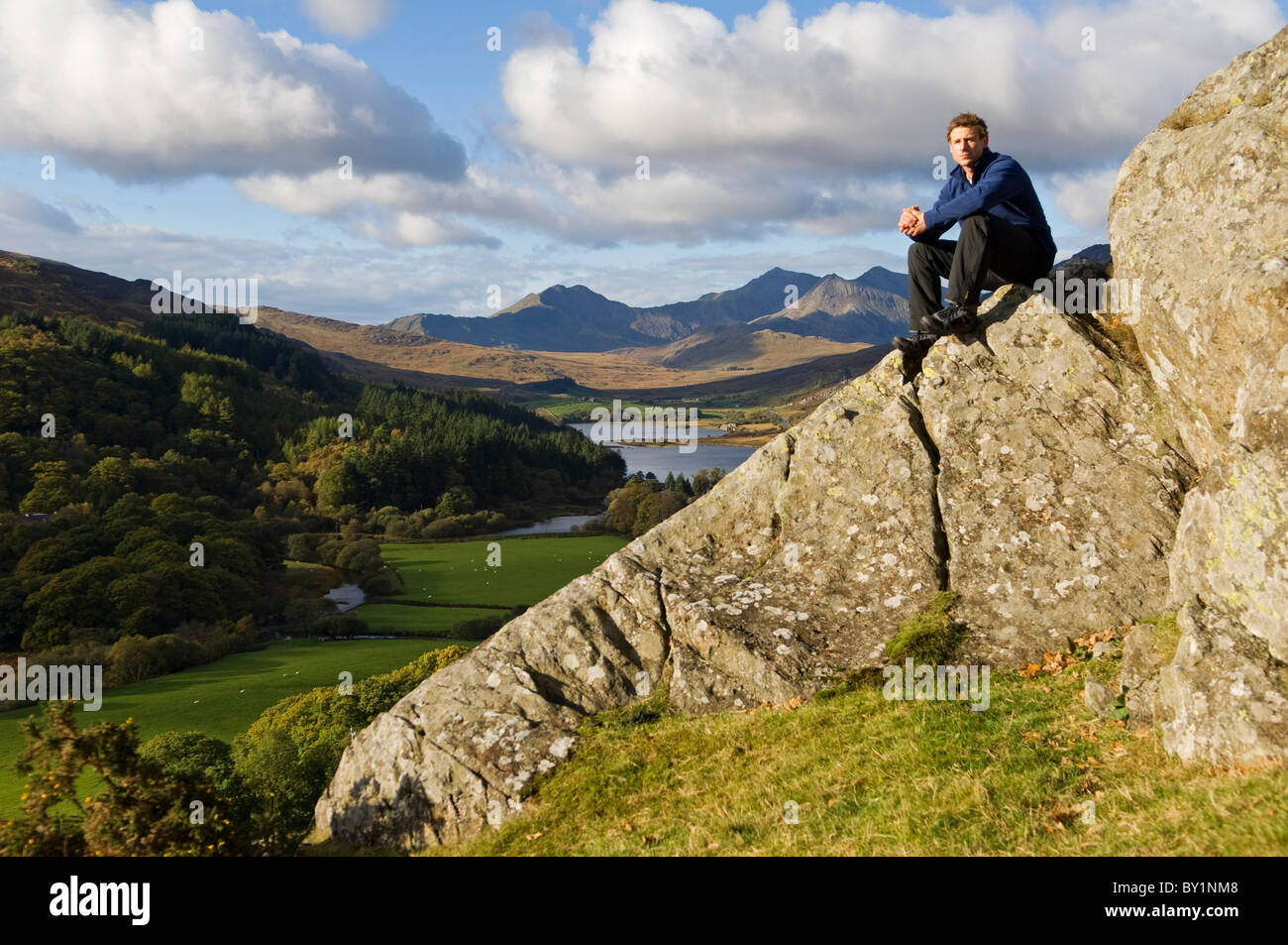 North Wales, Snowdonia.  Man sitting on rocks against the backdrop of Mt Snowdon. (MR) Stock Photo
