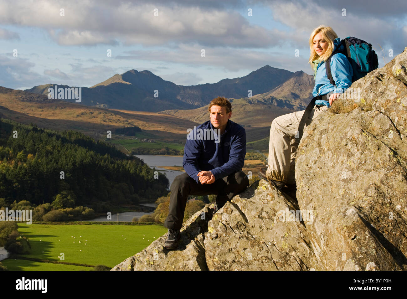 North Wales, Snowdonia.  Man and woman sitting on rocks against the backdrop of Mt Snowdon. (MR) Stock Photo