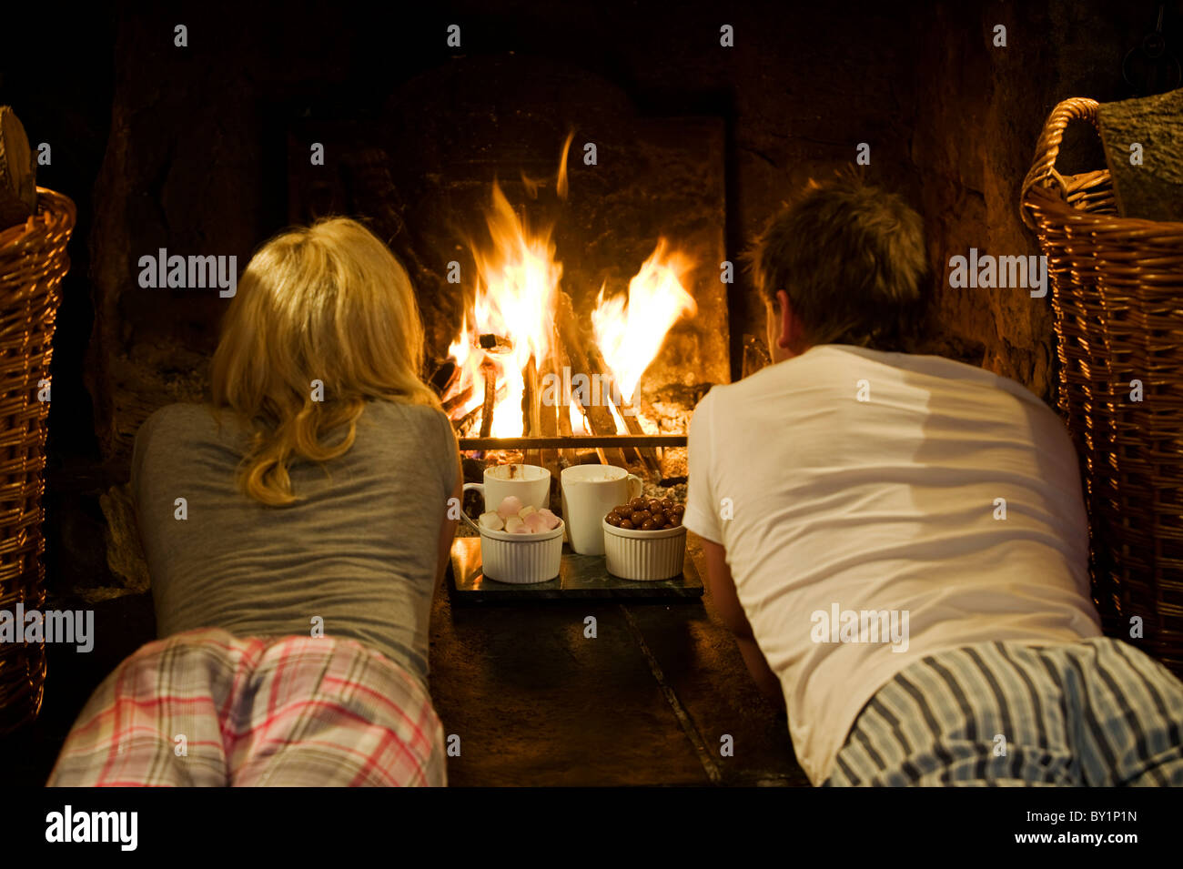 Gilar Farm, Snowdonia, North Wales.  A couple enjoy hot chocolate, marshmallows and maltesers by the open fire in the sitting Stock Photo
