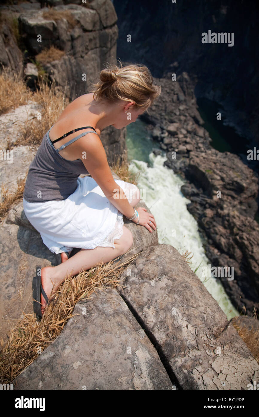 Zimbabwe, Victoria Falls. A young lady peers over the edge of Victoria Falls. MR Stock Photo