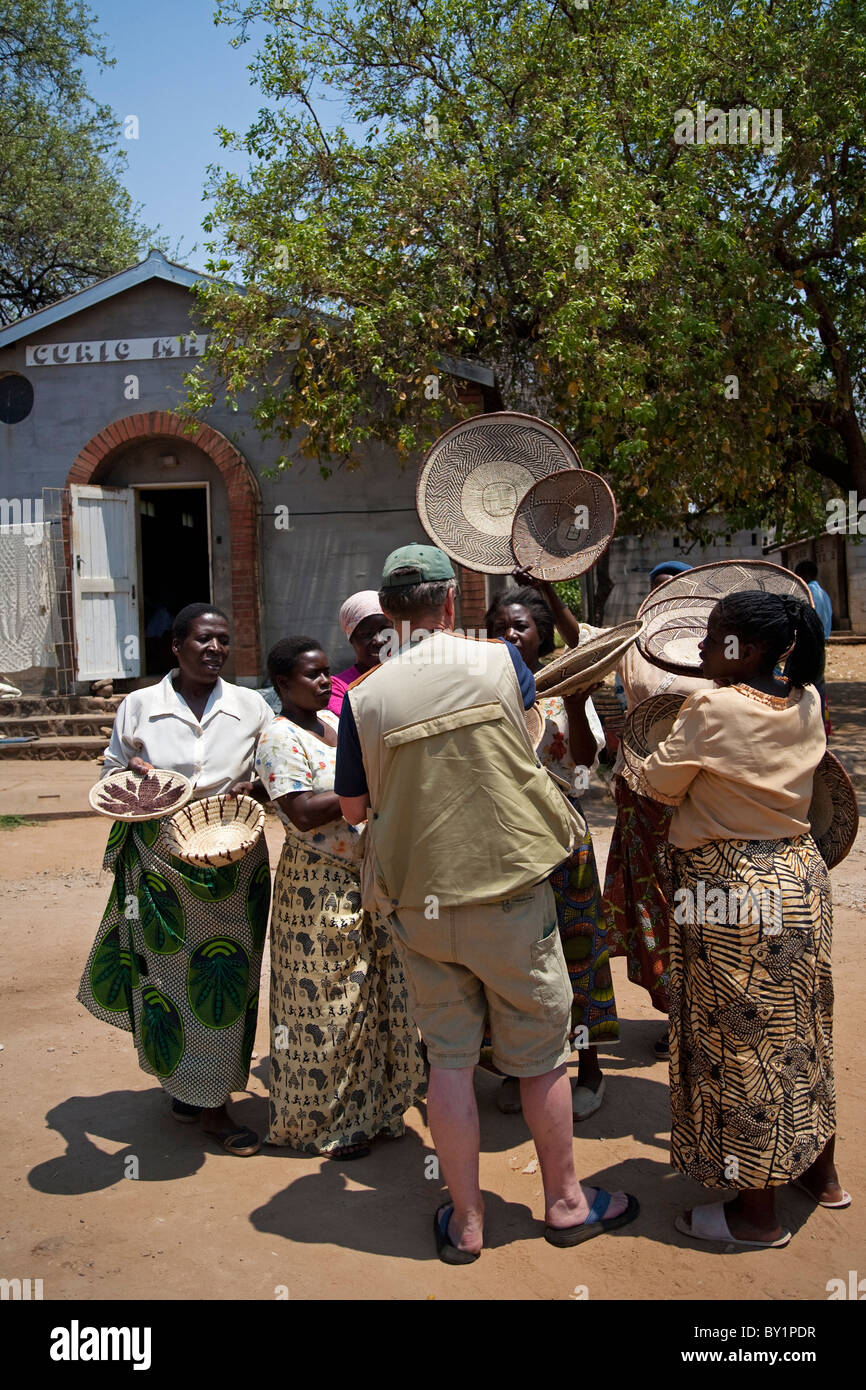 Zimbabwe, Victoria Falls. A man tries to choose a woven basket to buy at a Zimbabwean market. MR. Stock Photo