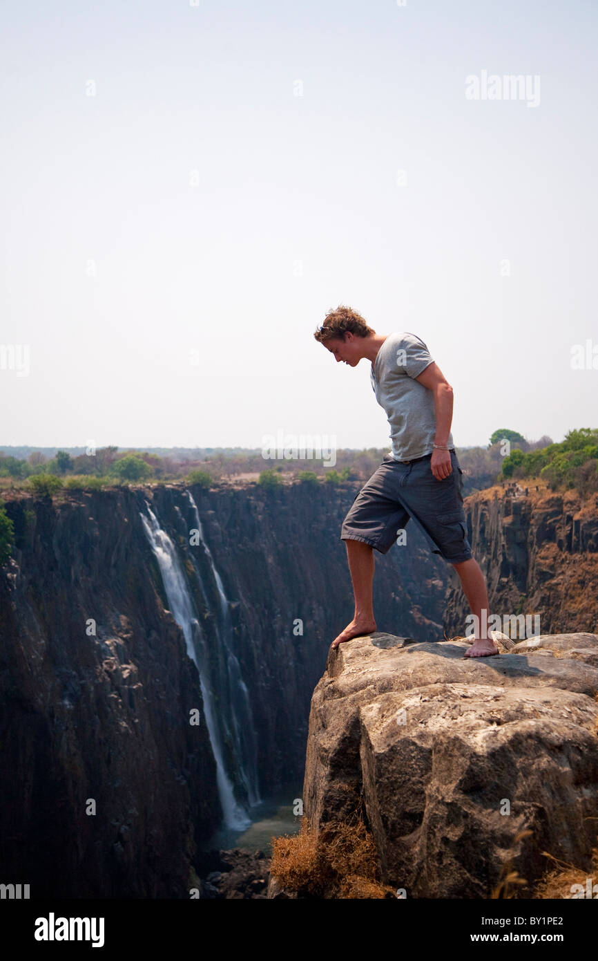 Zimbabwe, Victoria Falls. A man peers over the edge of Victoria Falls. MR. Stock Photo