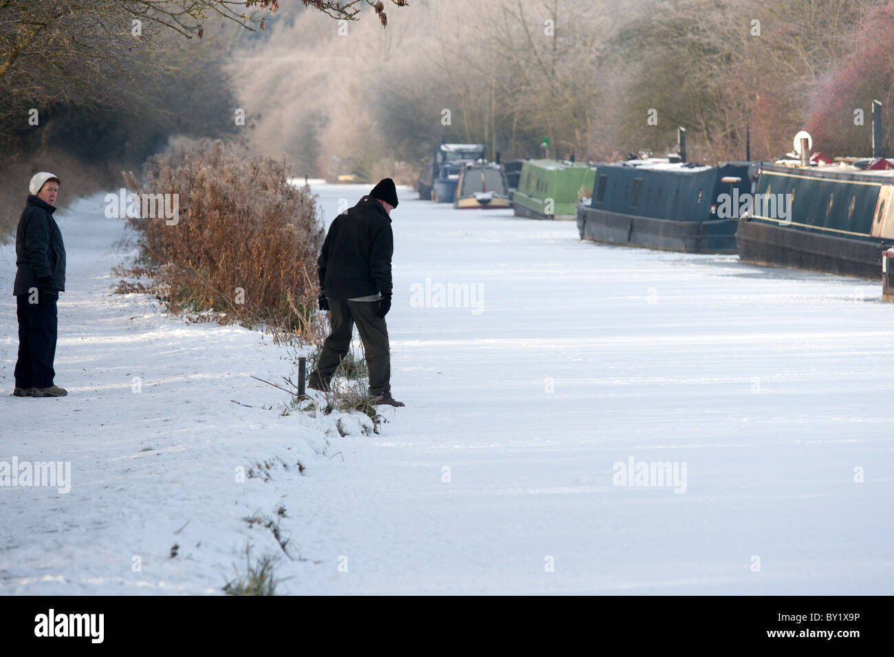 Freezing conditions led to the canals being frozen. Pictured, walkers test the frozen canal at Sutton Cheney, Leicestershire. Stock Photo
