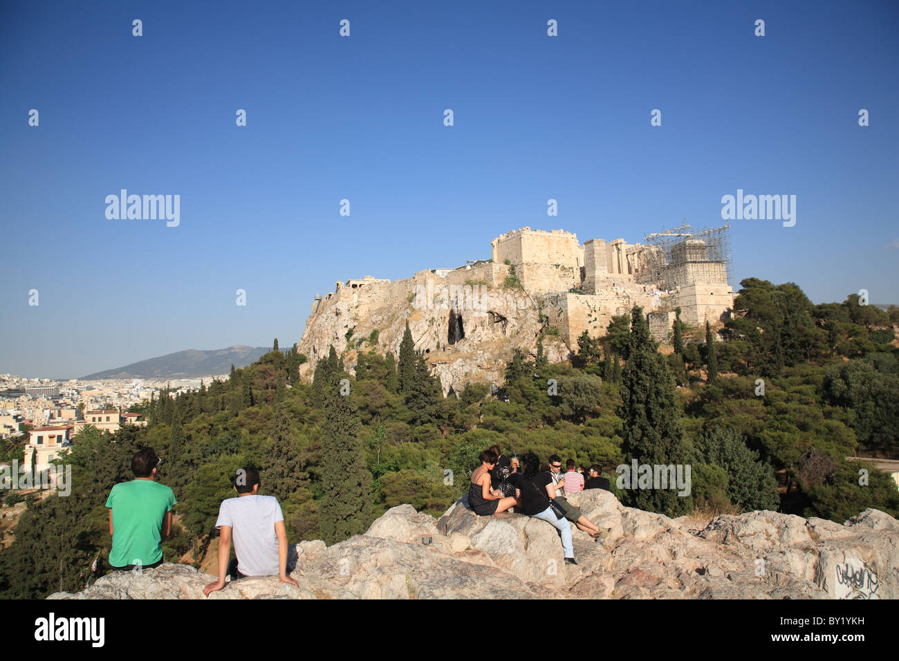 Young people in the late afternoon overlooking the Acropolis mound of Athens or Citadel of Athens and overview of Athens, Greece Stock Photo