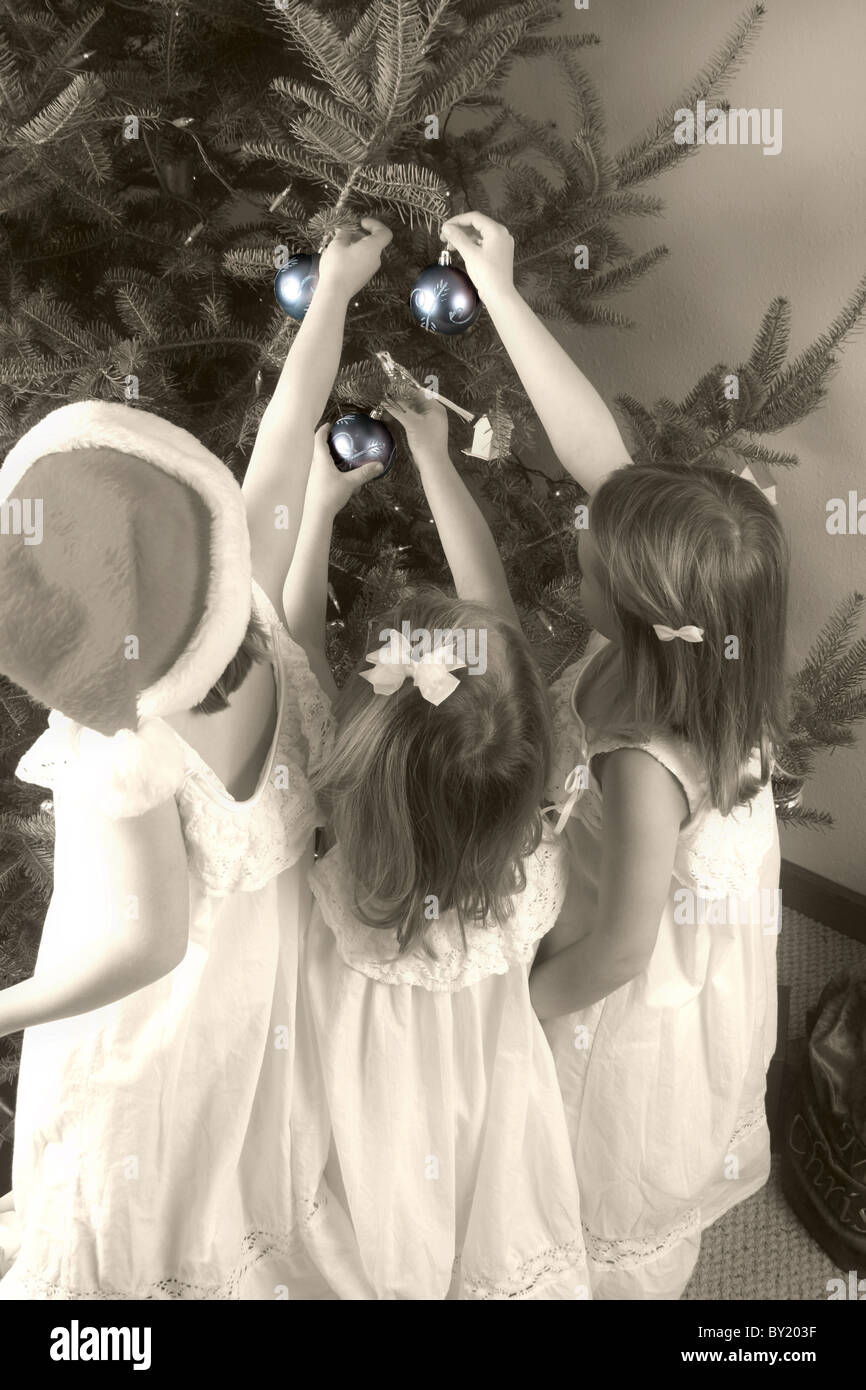 Three children placing Christmas ornaments on the tree Stock Photo Alamy