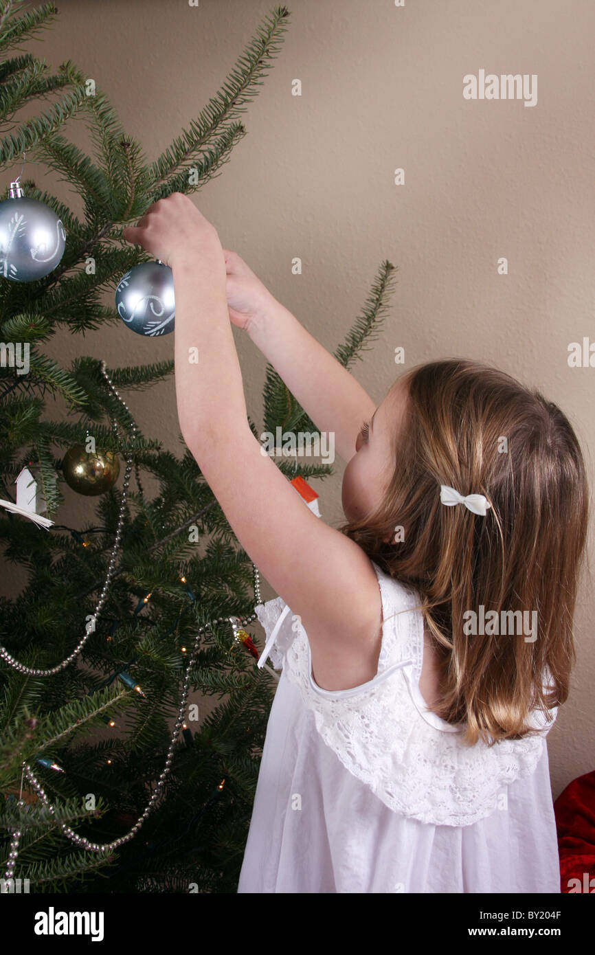 A child placing a Christmas ornament on the tree Stock Photo Alamy