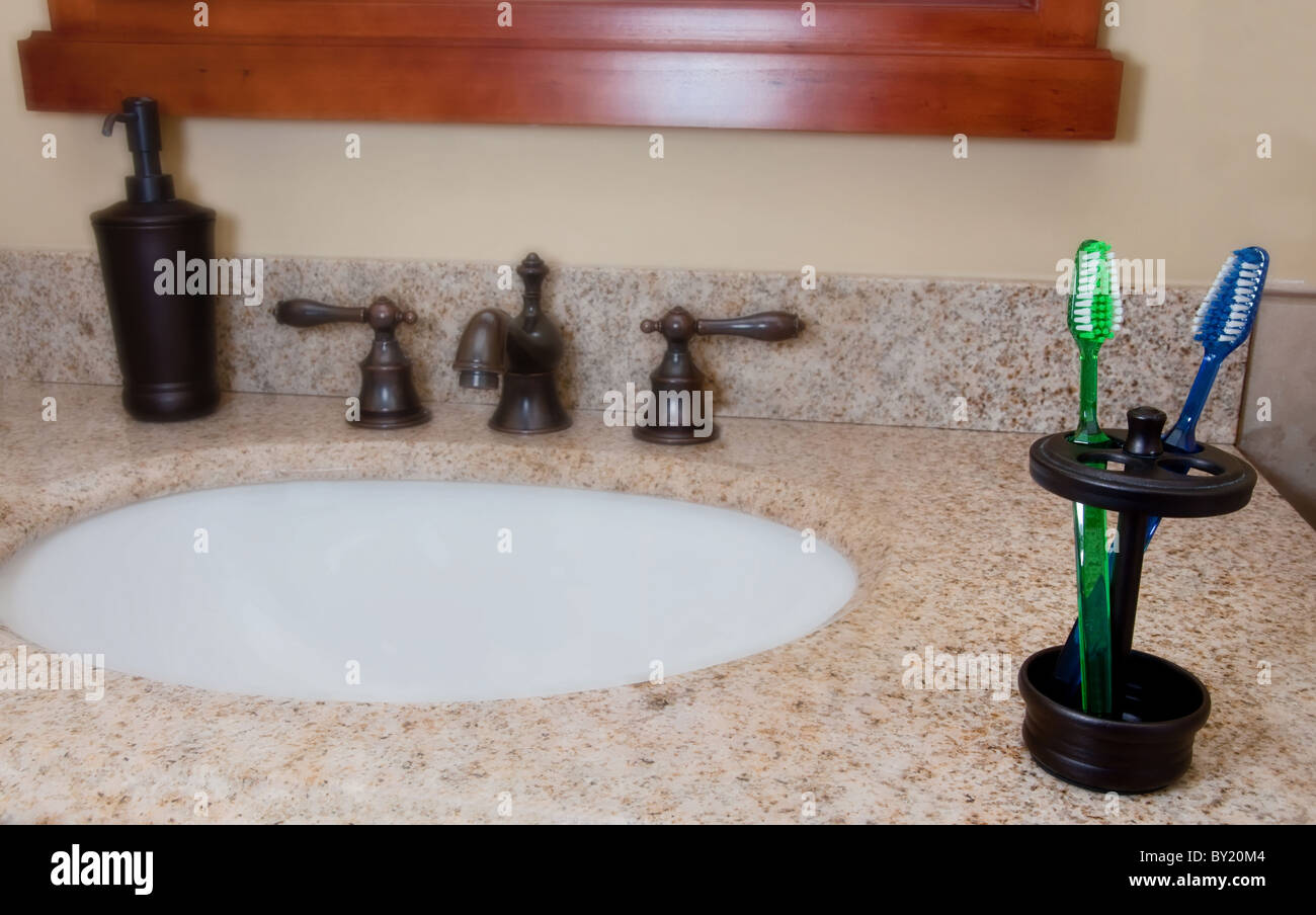 Bathroom sink and faucet with toothbrushes and soap dispenser. Stock Photo
