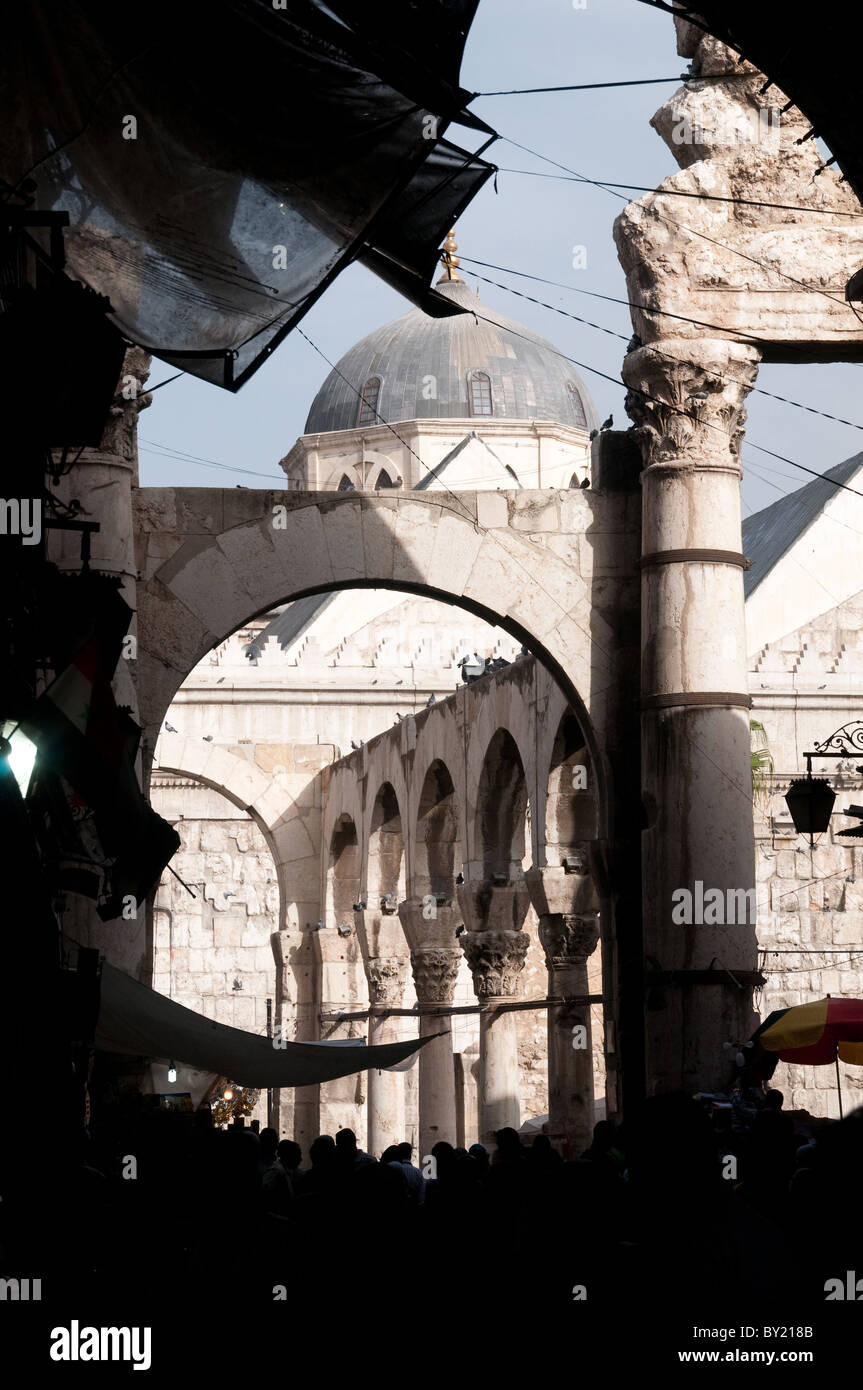 A crowd of people walking along the walls of the Umayyad mosque and the ancient Roman ruins of the Temple of Jupiter, old city of Damascus, Syria. Stock Photo
