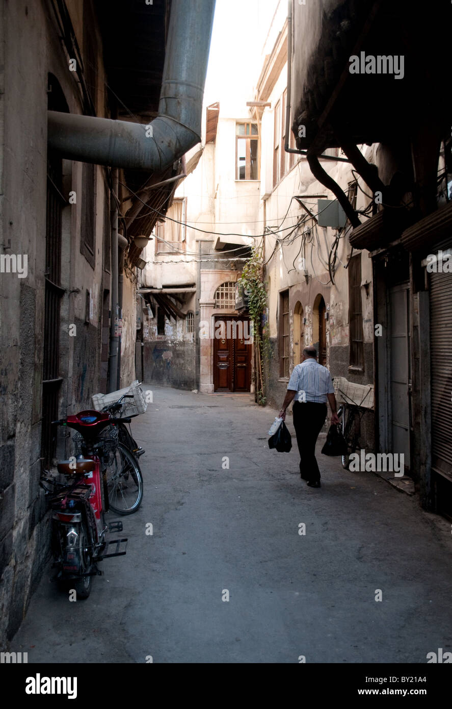 A man walking home carrying groceries in a narrow alleyway in the Bab Touma district of the old city of Damascus, Syria. Stock Photo