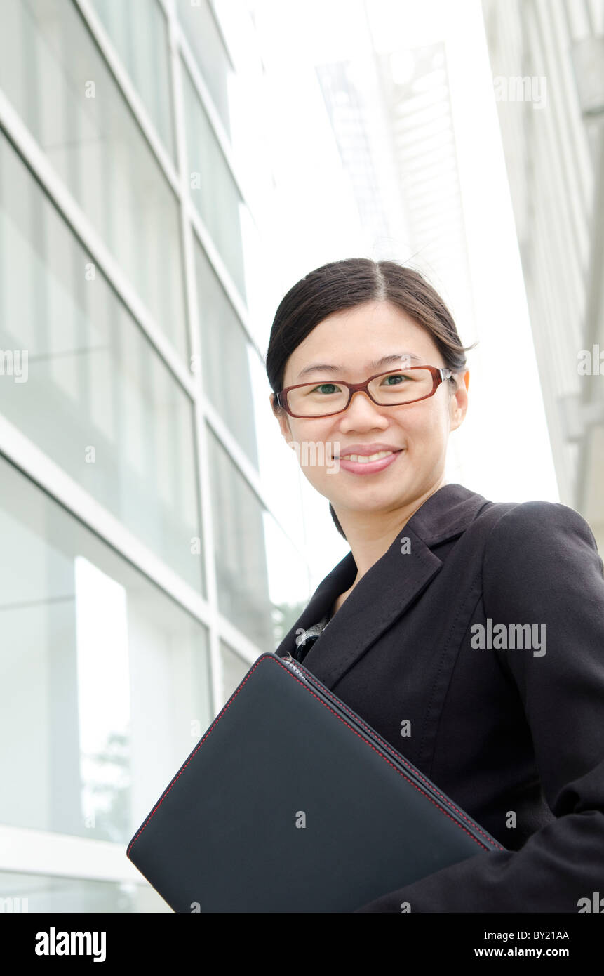 Asian executive smiles and standing outdoors Stock Photo