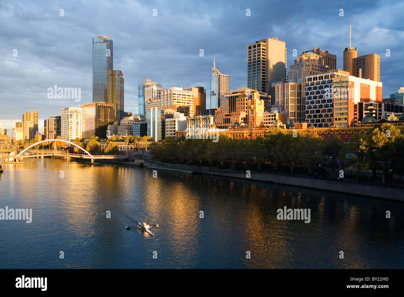 Australia, Victoria, Melbourne.  Morning rower on the Yarra River with city skyline beyond. Stock Photo